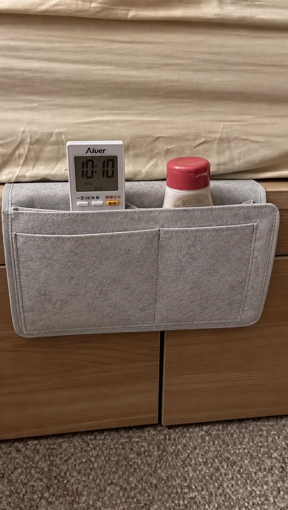 Organizador colgado al lado de la cama con un reloj y un frasco